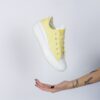 a woman's hand holding a yellow tennis shoe