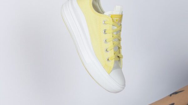 a woman's hand holding a yellow tennis shoe