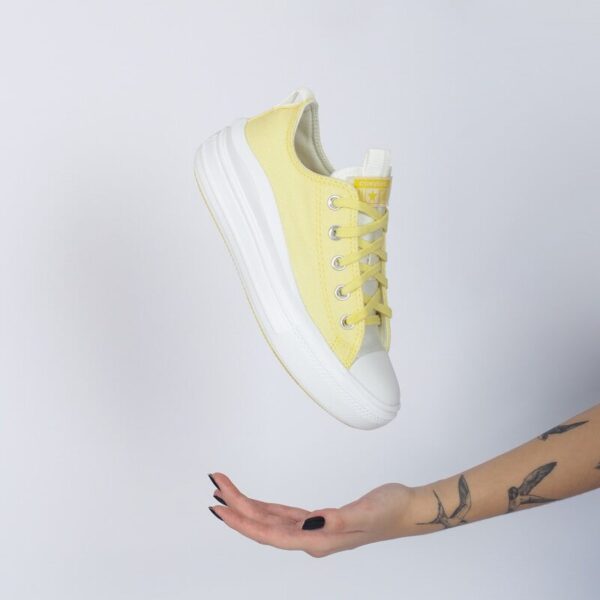 a woman's hand holding a yellow tennis shoe