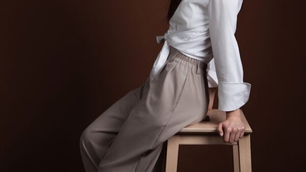 A woman poses elegantly on a wooden stool.