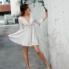 woman in white long sleeve dress holding flower