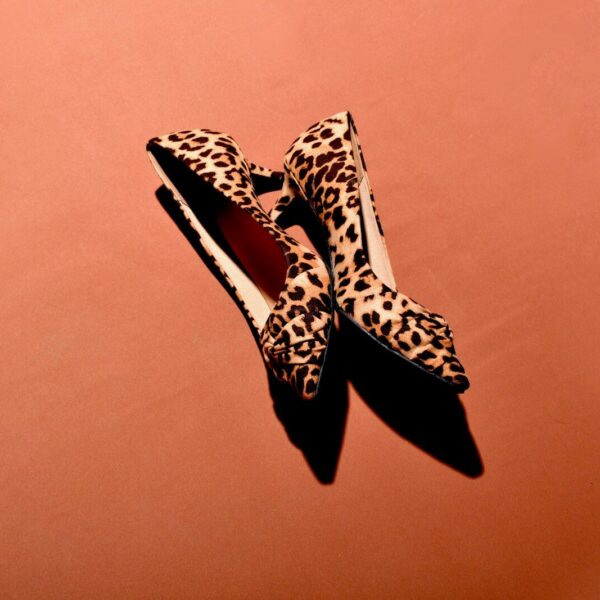 a pair of leopard print shoes on a pink background