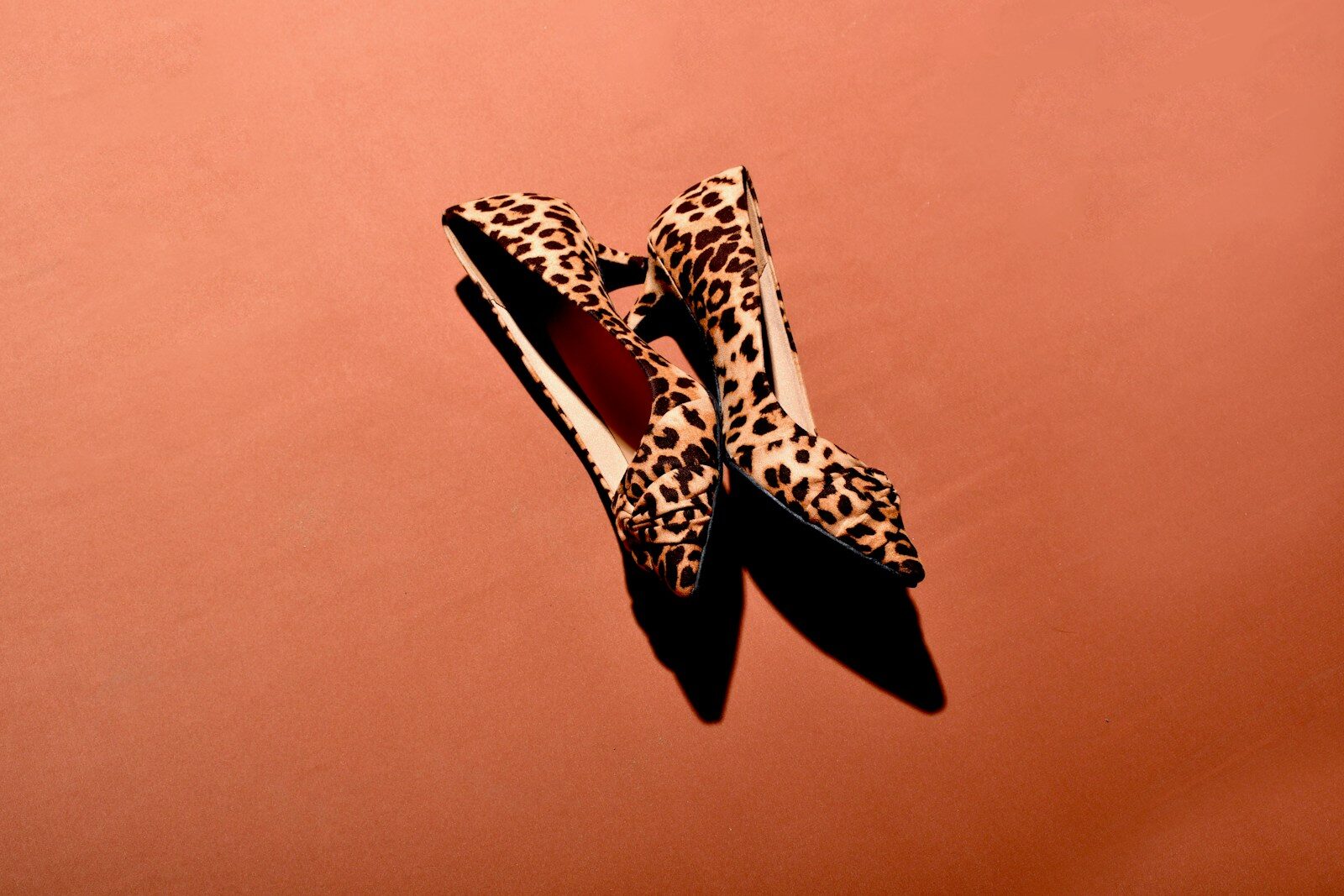 a pair of leopard print shoes on a pink background