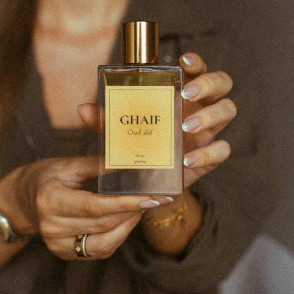 Hands holding ghaif oud alif perfume bottle