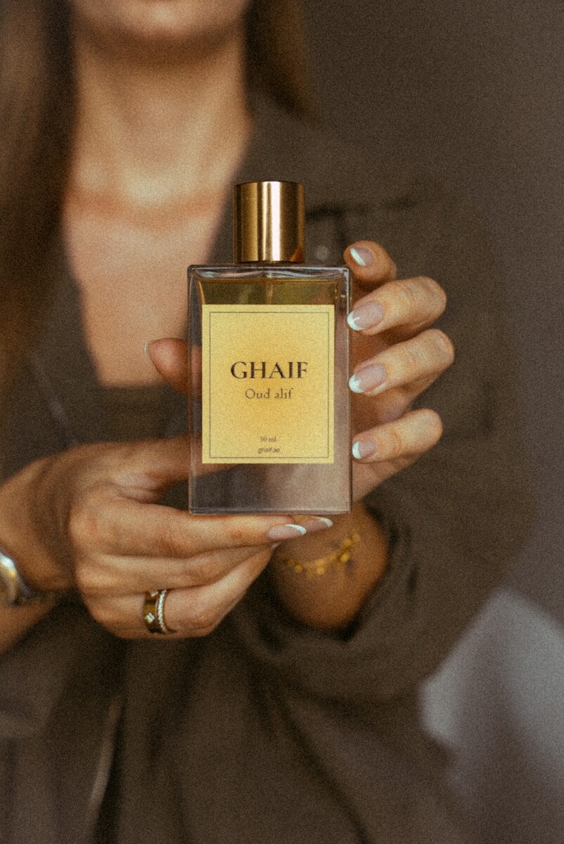 Hands holding ghaif oud alif perfume bottle