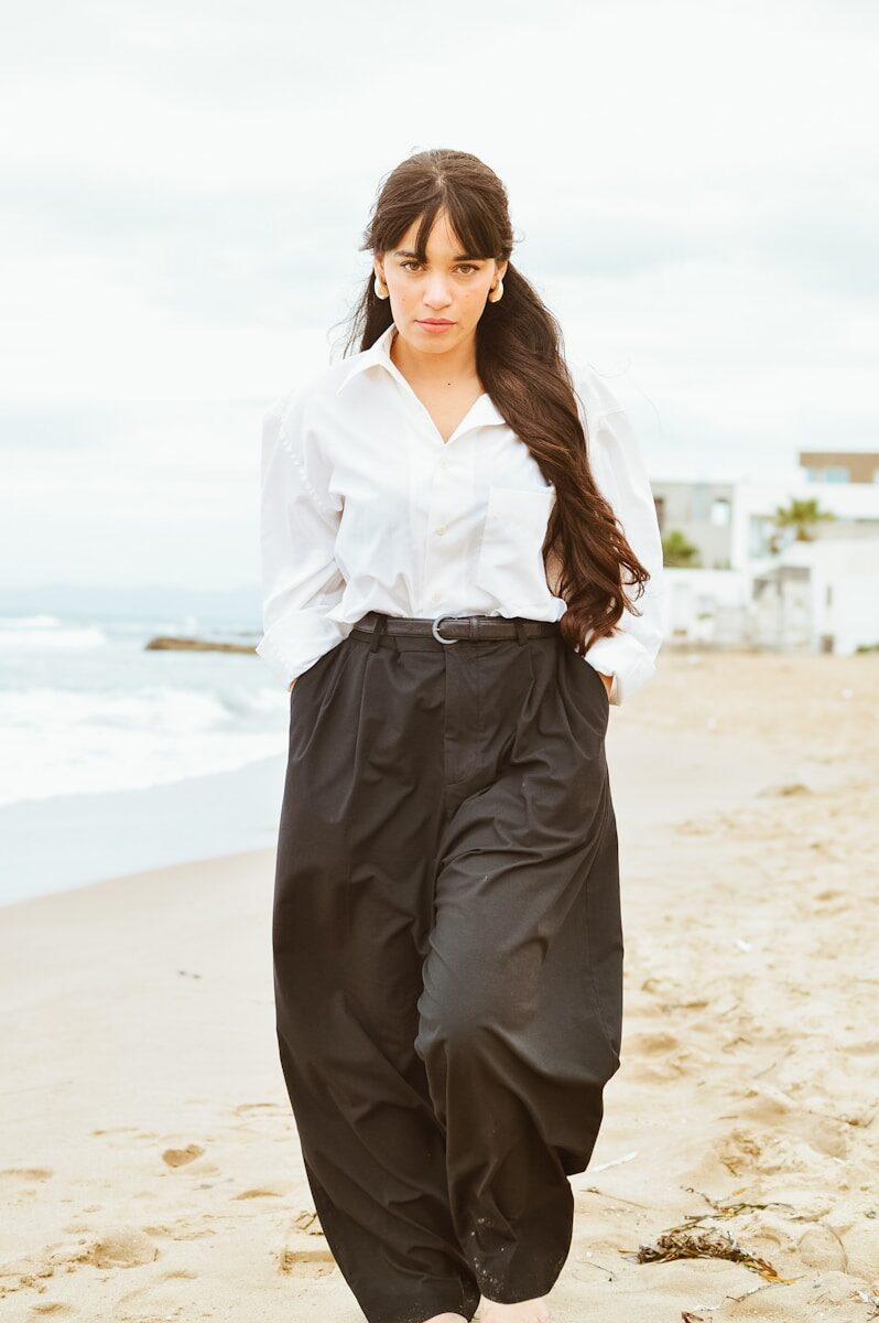 A woman standing on a beach next to the ocean