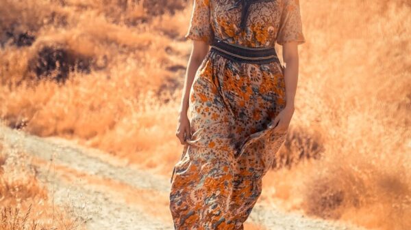 woman in brown and black floral dress standing on dirt road during daytime