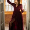 Woman in a burgundy dress with a high slit dances.