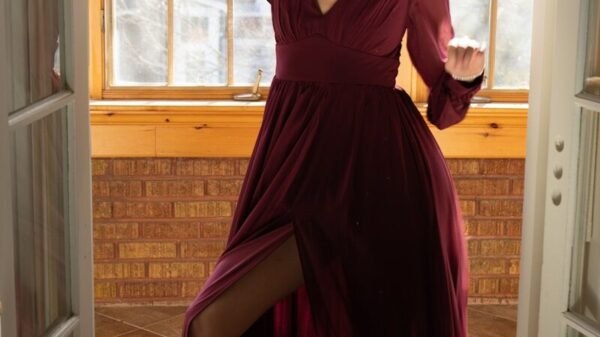 Woman in a burgundy dress with a high slit dances.