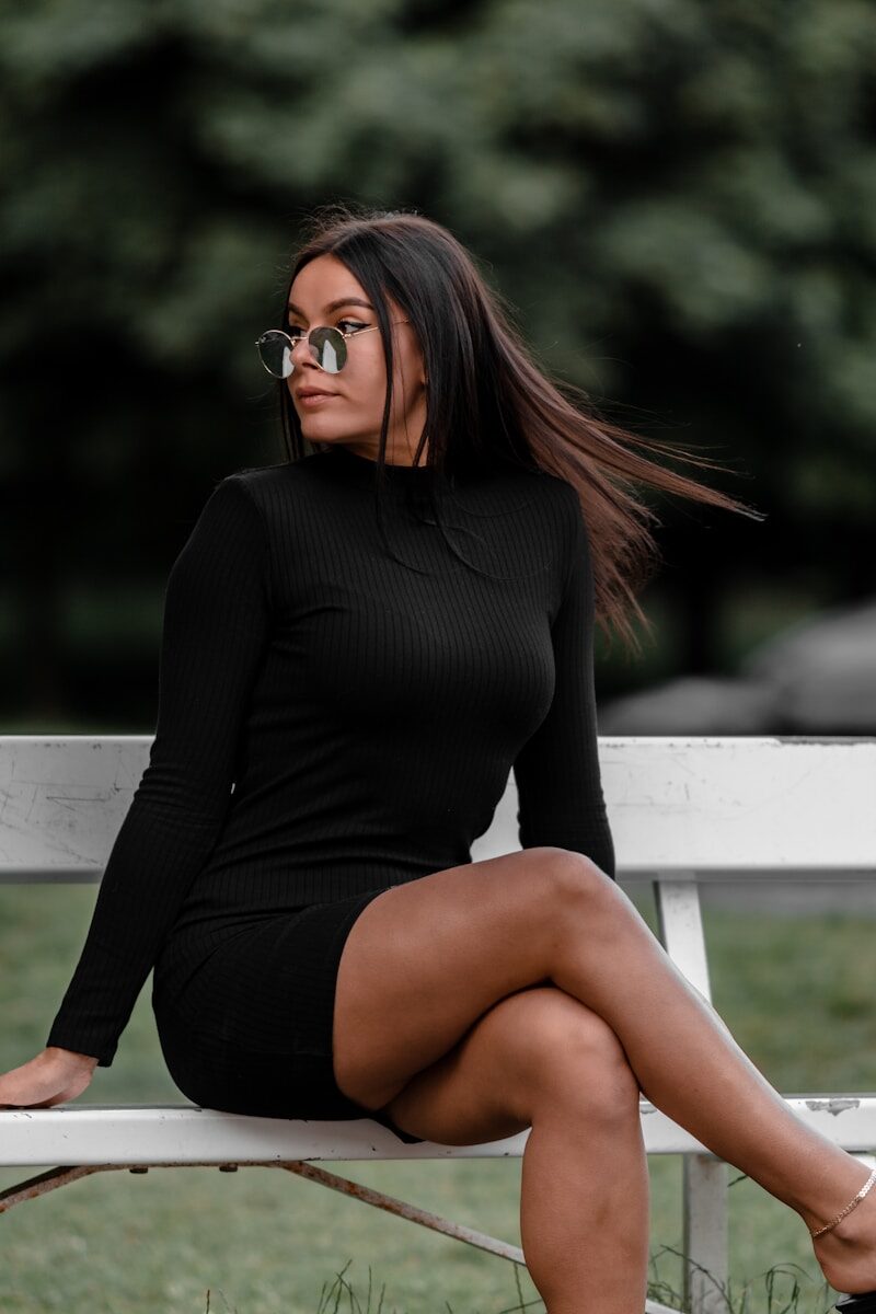 woman in black long sleeve shirt sitting on white wooden bench during daytime