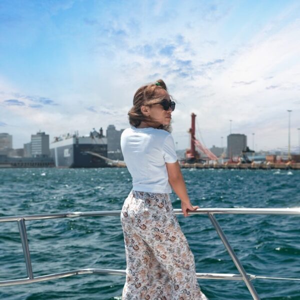 woman in white shirt and brown floral skirt standing on boat during daytime