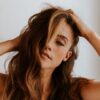 a woman with long brown hair holding her head