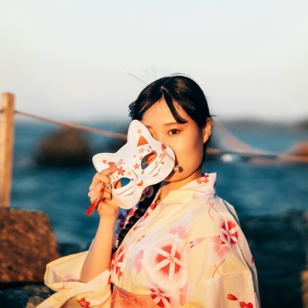 a woman in a kimono is holding a mask