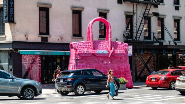 A woman crossing the street in front of a pink bag