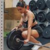 a woman squats on a barbell in a gym