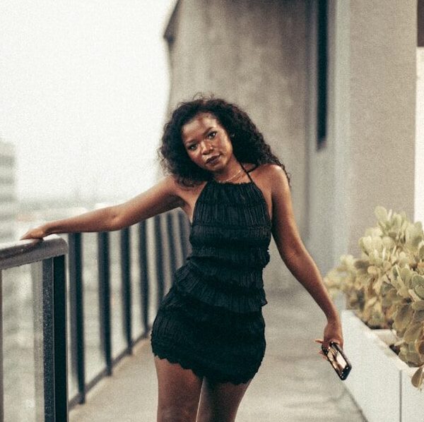 Woman poses on a balcony overlooking a cityscape.