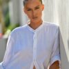 Woman in white shirt leaning against wall