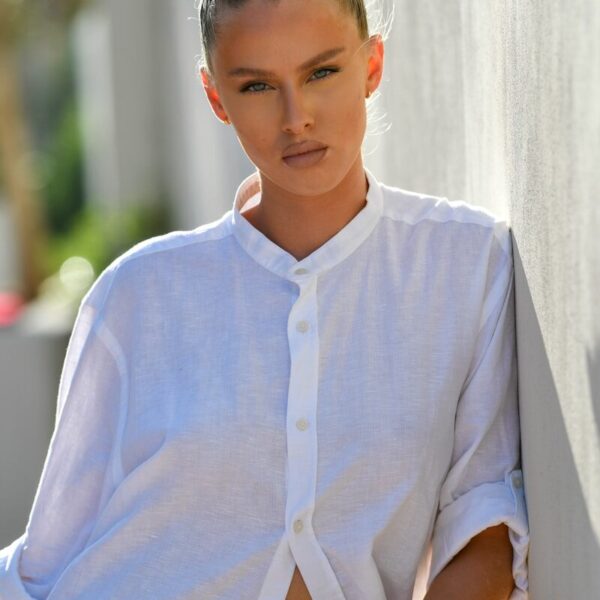 Woman in white shirt leaning against wall