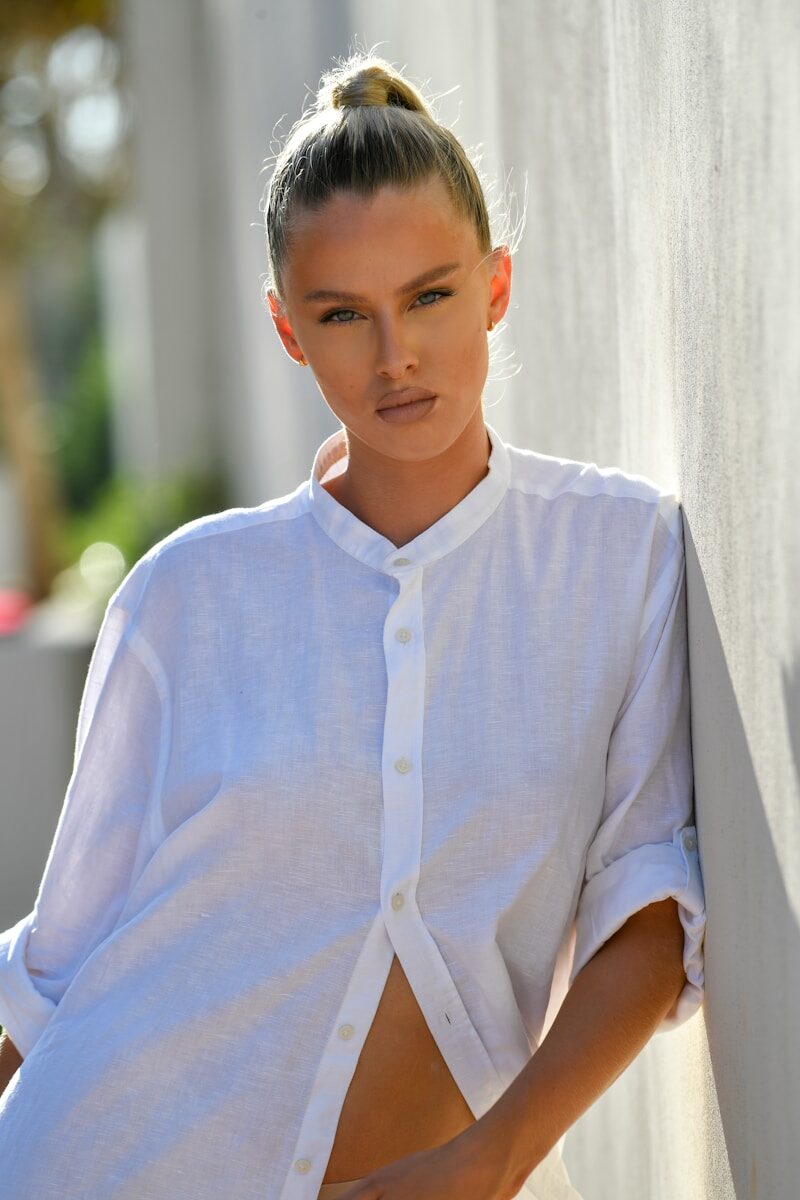 Woman in white shirt leaning against wall