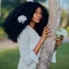 Woman with flowers in hair embraces tree, exuding natural beauty and elegance.