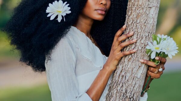 Woman with flowers in hair embraces tree, exuding natural beauty and elegance.